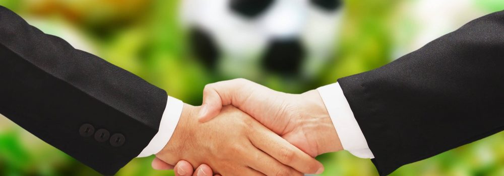 business man hand shake with soccer blur background